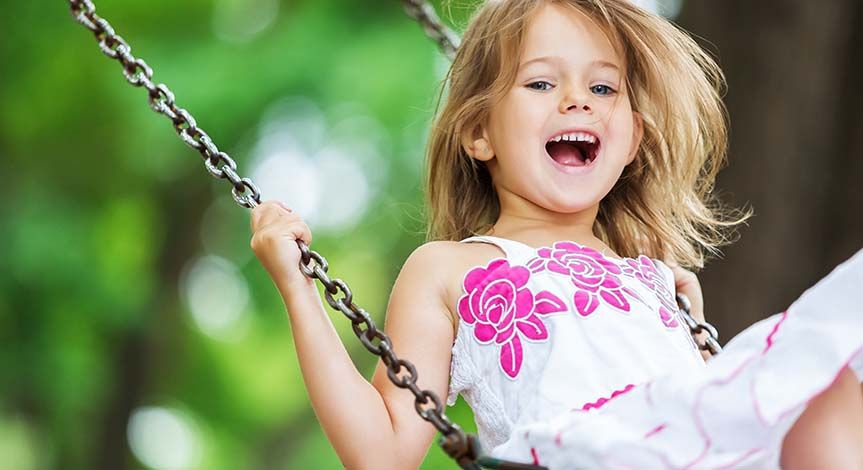 Girl in flowered dress having fun on a swing