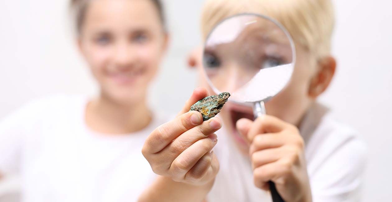 Boy looking at rock through a magnifying glass